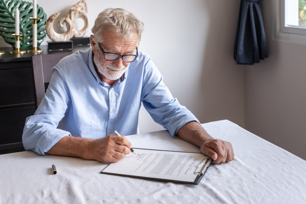 older man signing his last will and testament from kitchen table