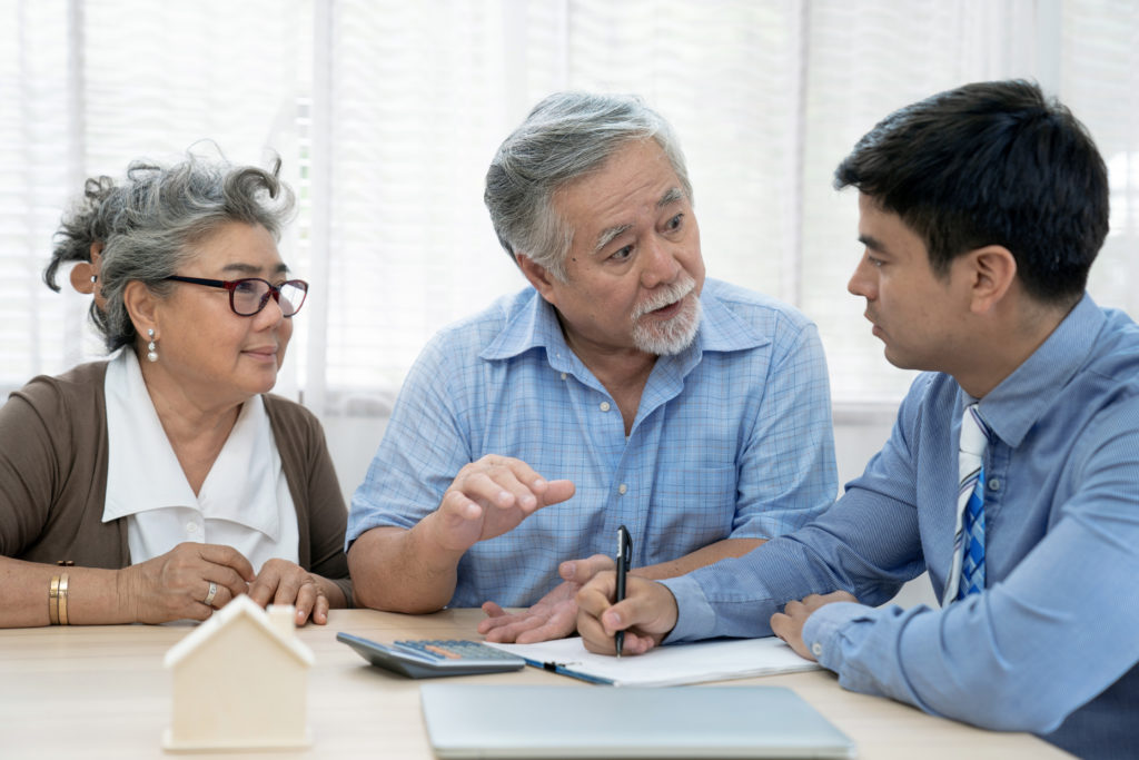 asian couple talks with estate planning expert at a kitchen table